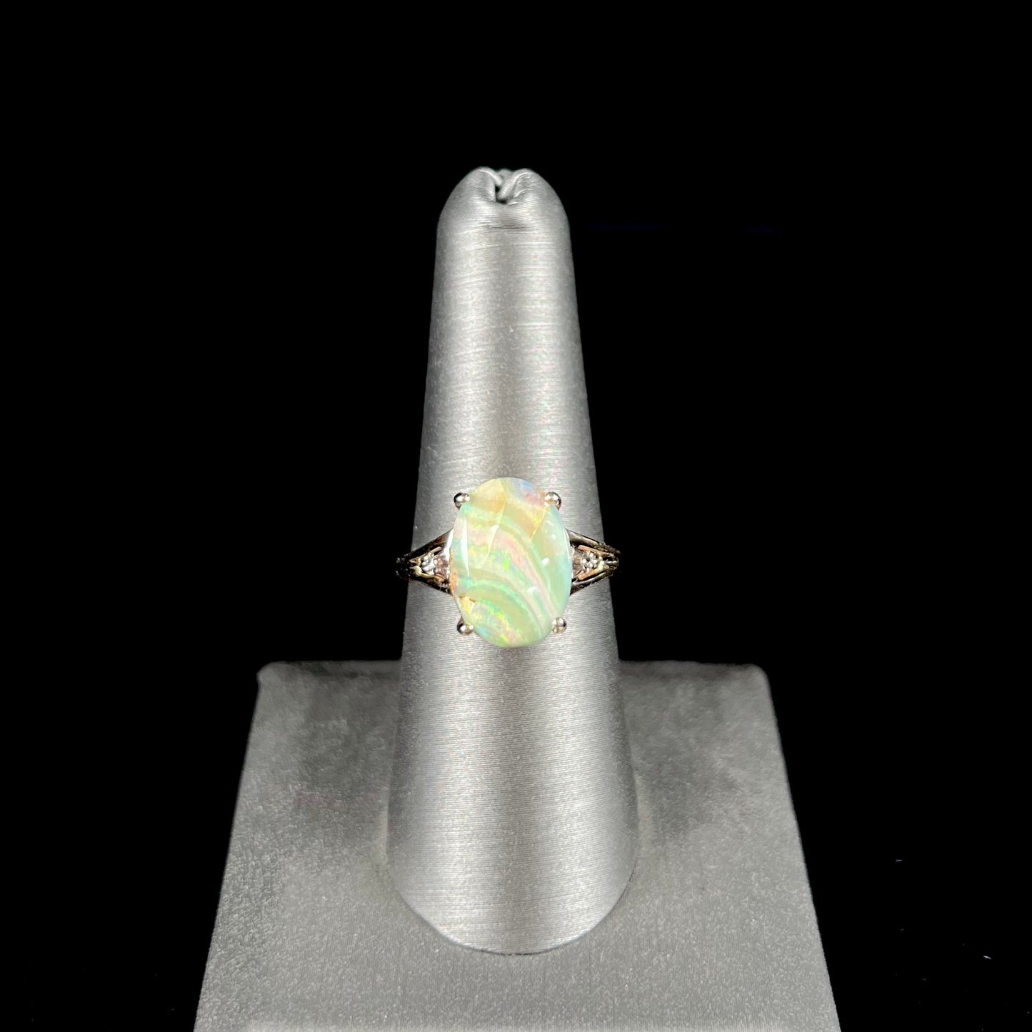 A ladies' Australian boulder opal ring set in yellow gold with diamond accents.  The opal shimmers green and pink and has fissure inclusions.