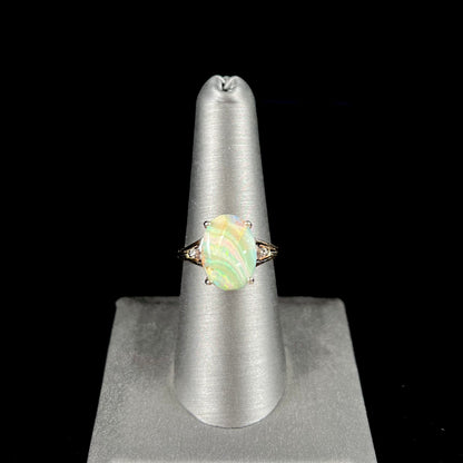 A ladies' Australian boulder opal ring set in yellow gold with diamond accents.  The opal shimmers green and pink and has fissure inclusions.