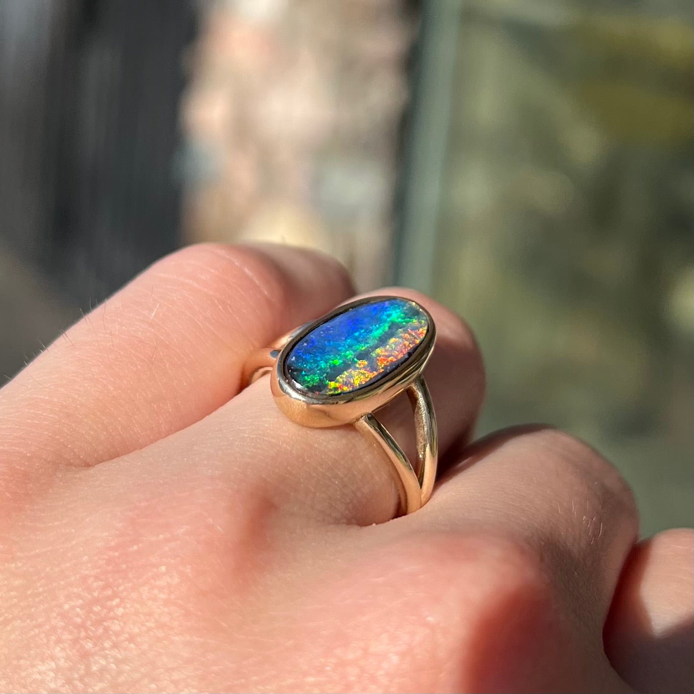 A ladies' yellow gold split shank solitaire ring set with a natural Australian black boulder opal.