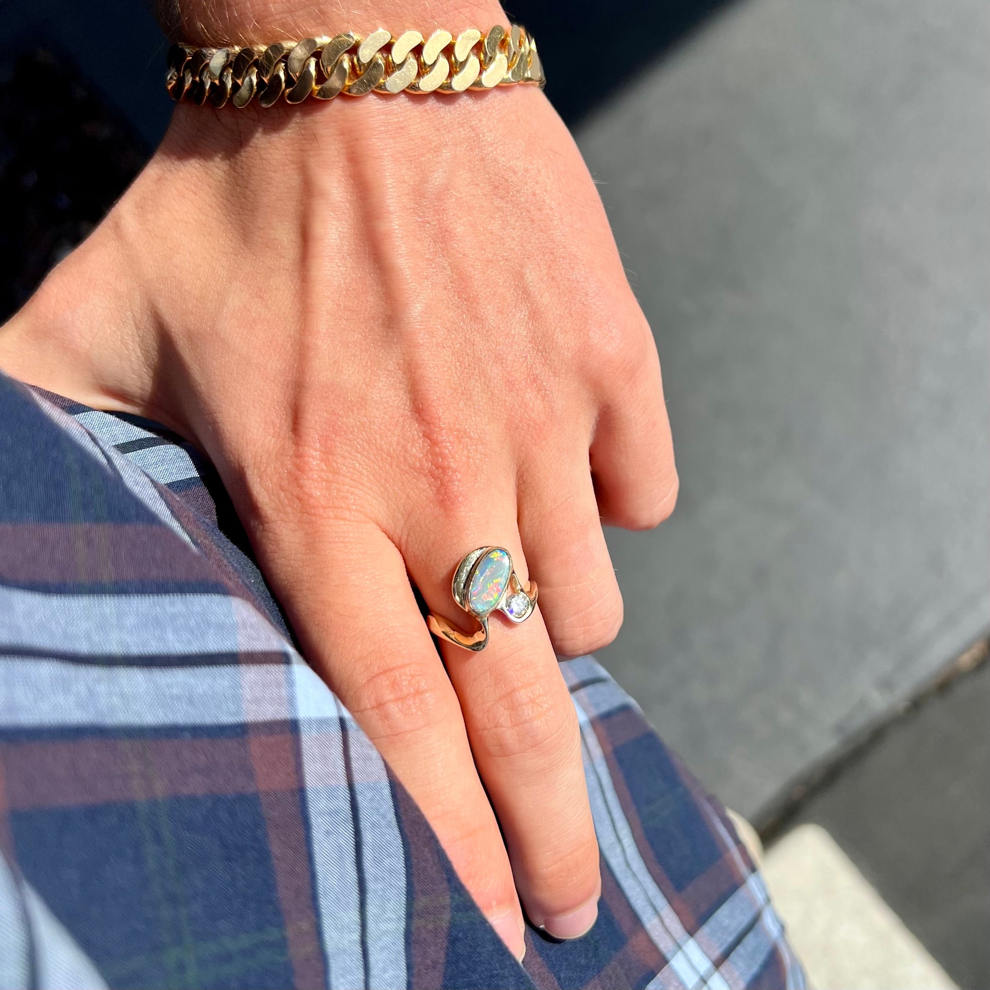 A ladies' yellow gold, bezel set ring mounted with a natural 1.15 carat black opal and round diamond.