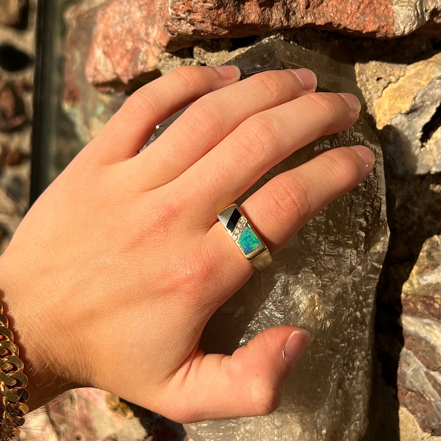 A men's yellow gold ring inlay set with onyx, natural black opal, and four diamonds.