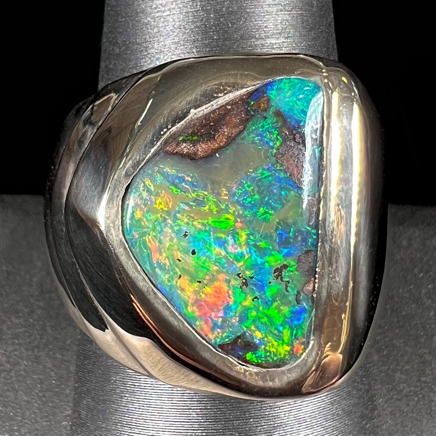 A men's yellow gold solitaire ring set with a triangular shaped natural boulder opal.