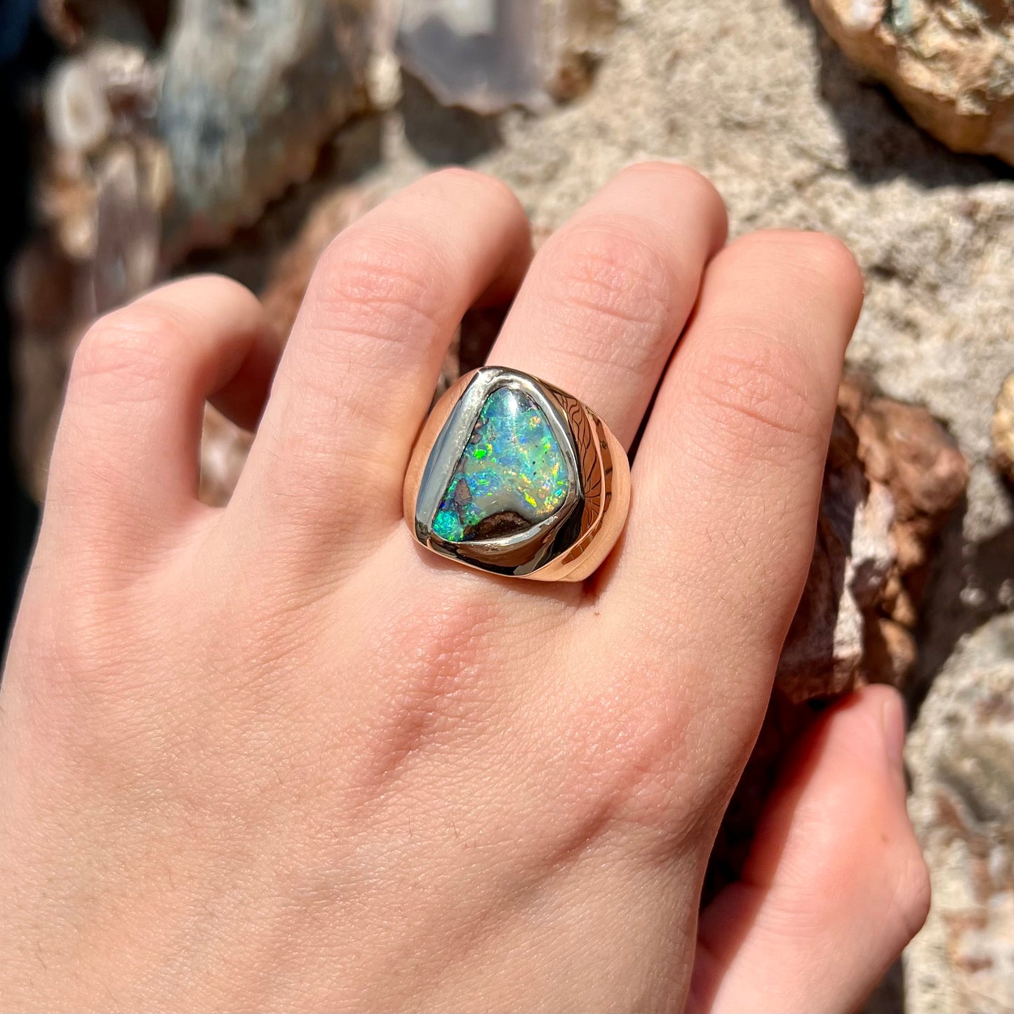 A men's yellow gold solitaire ring set with a triangular shaped natural boulder opal.