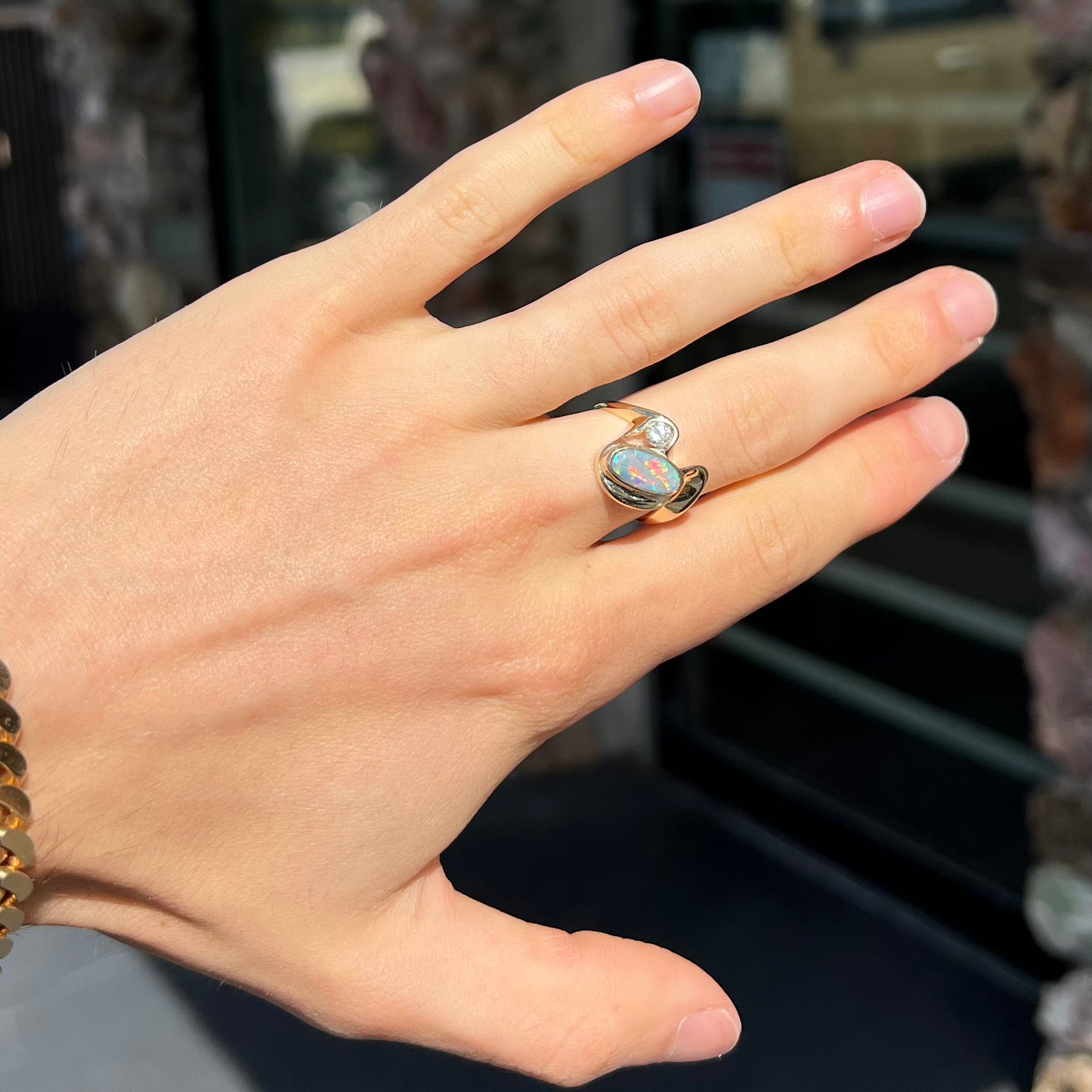 A ladies' yellow gold, bezel set ring mounted with a natural 1.15 carat black opal and round diamond.