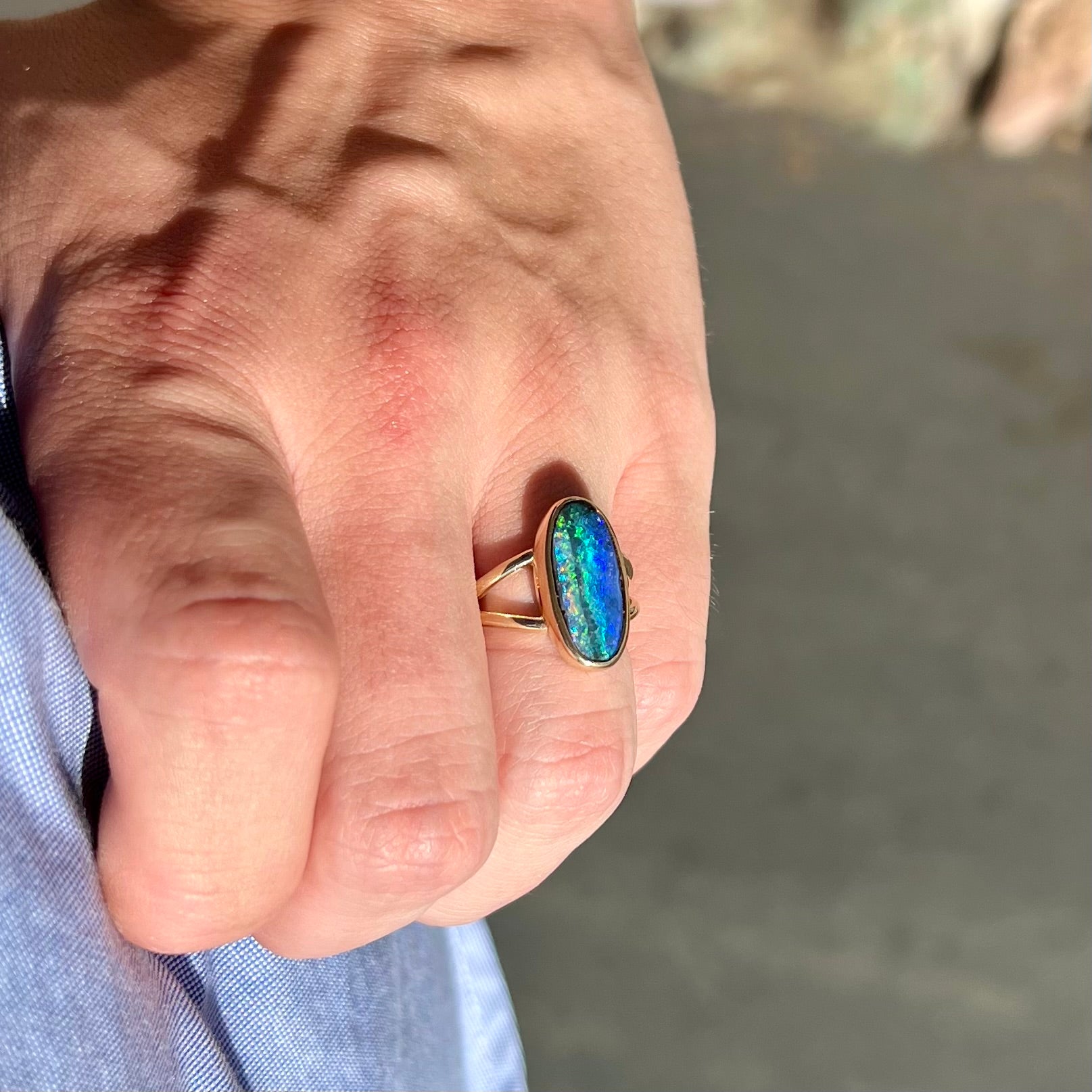 A ladies' yellow gold split shank solitaire ring set with a natural Australian black boulder opal.