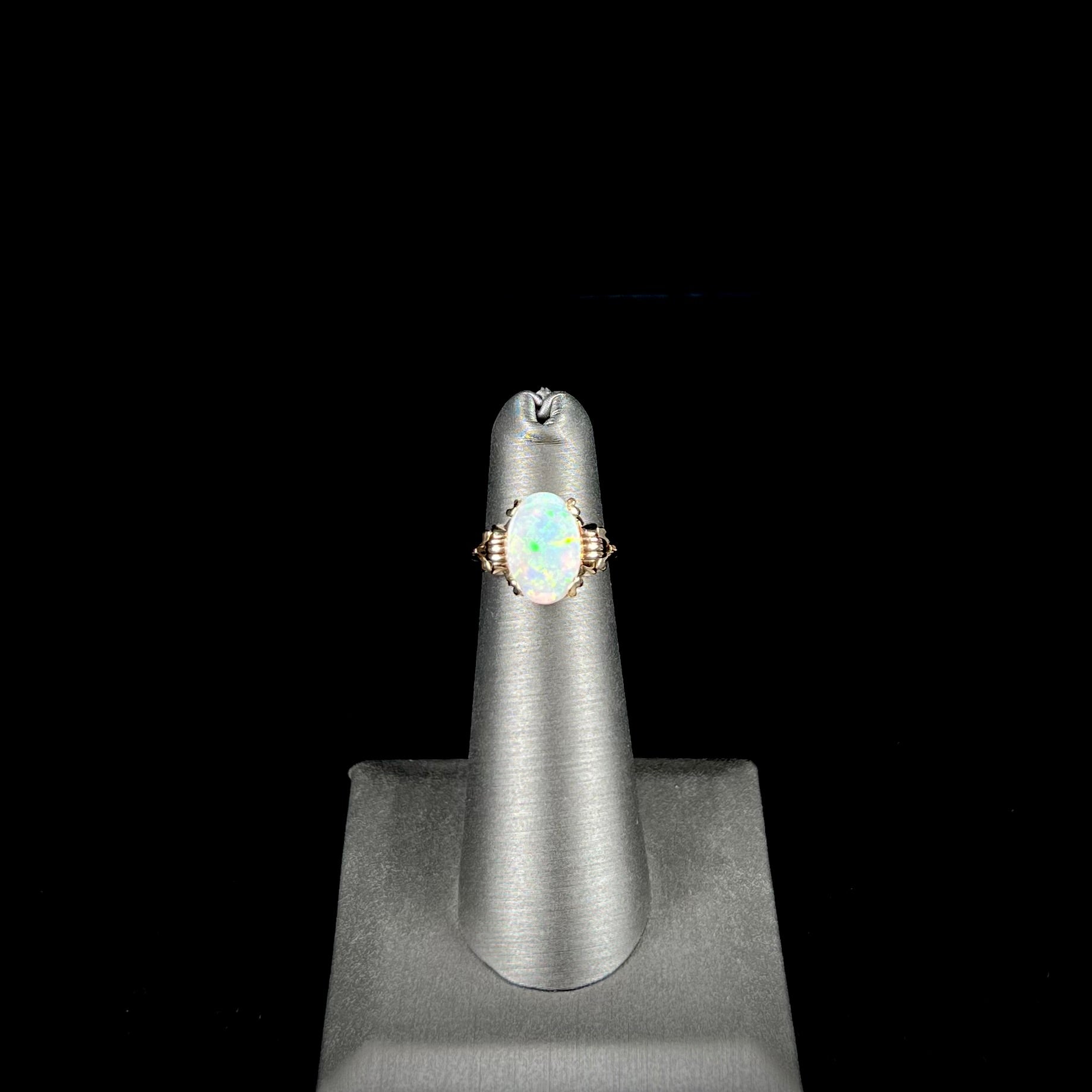 A ladies' Art Deco style natural opal solitaire ring in yellow gold.  The opal is oval cut.