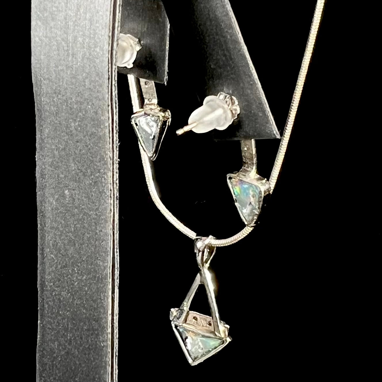 A white gold pendant and earrings set mounted with triangle cut natural black opals and diamonds.