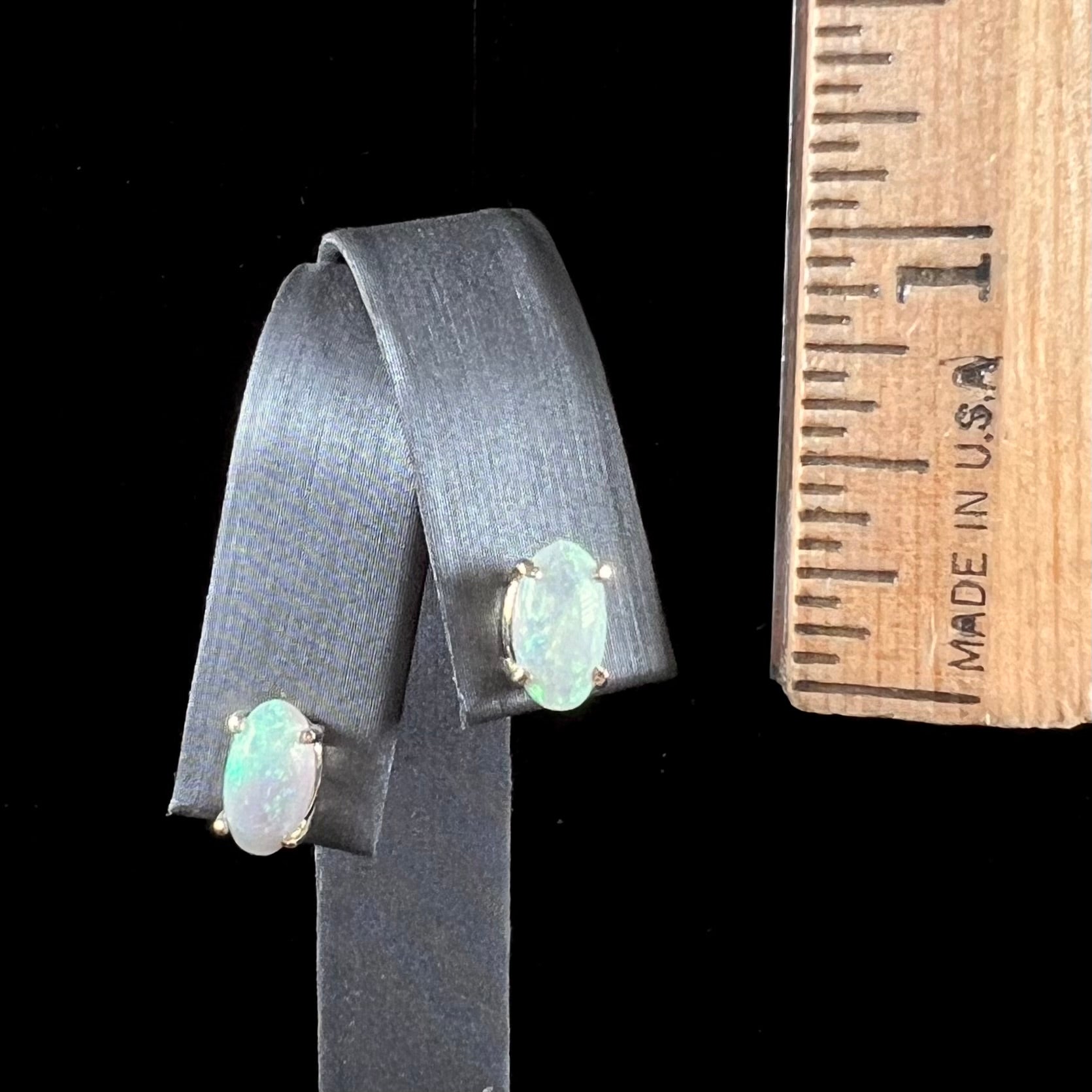 A pair of natural, semi-black crystal opal stud earrings in yellow gold.  The opals are oval cabochon cut.