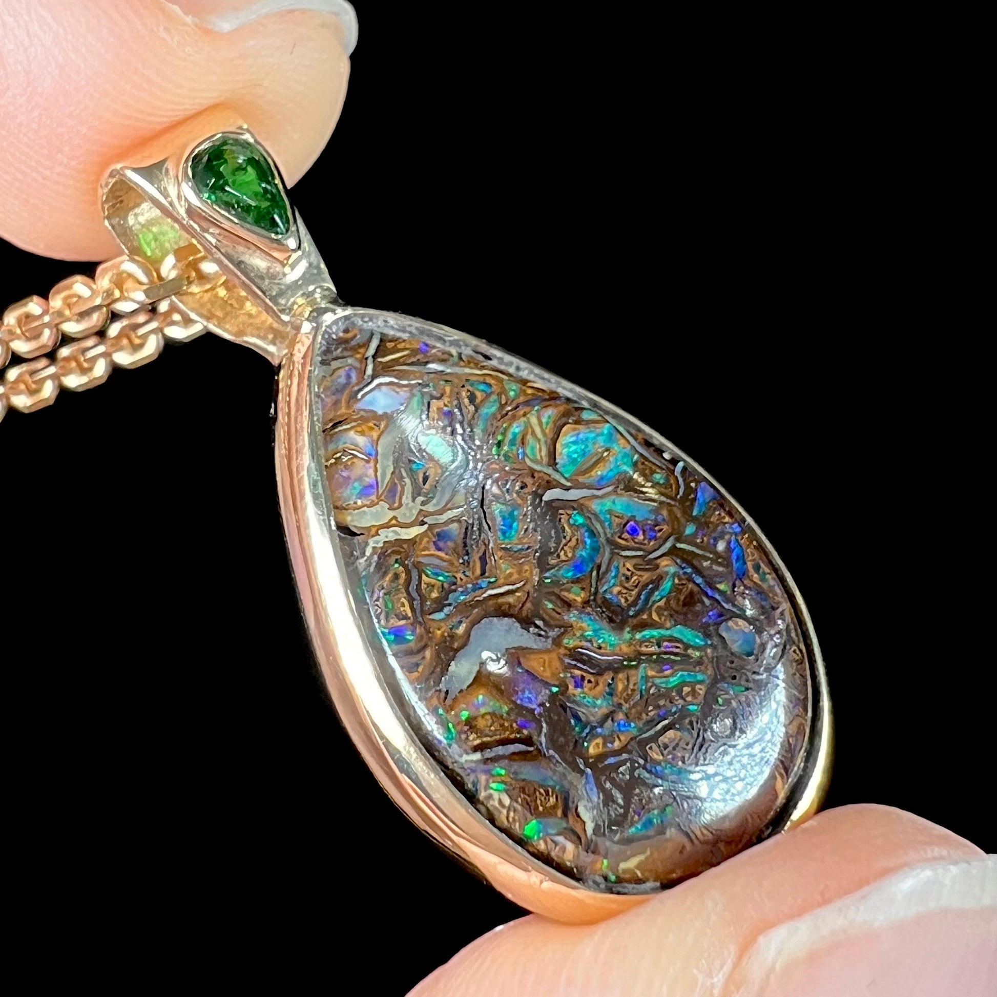 A ladies' yellow gold pendant set with a natural Koroit, Australian boulder opal and a tsavorite garnet accent stone.