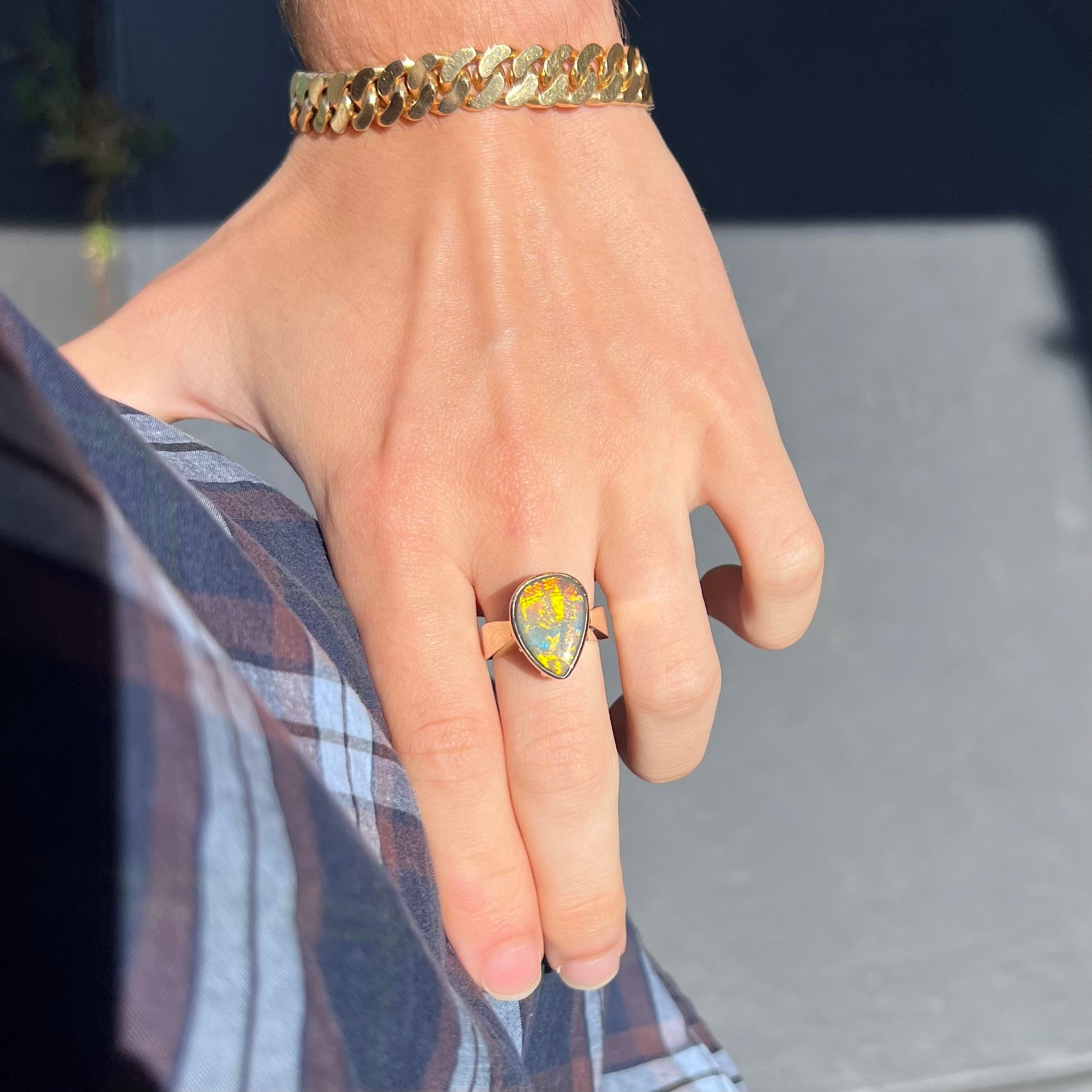 A large ladies' yellow gold solitaire ring set with a natural, pear shaped black crystal opal.  The opal has green and orange fire.