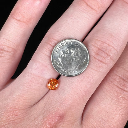 A faceted cushion cut natural orange sapphire gemstone.  The stone is cut to enhance the orange color.