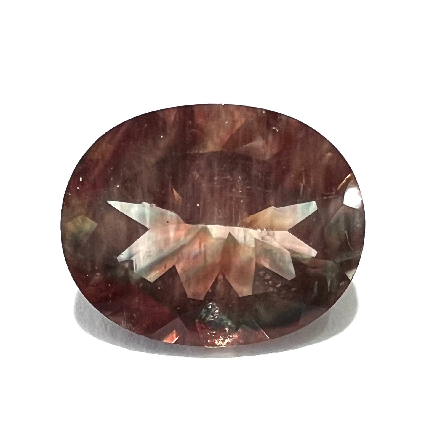 A loose, oval cut oregon sunstone.  The gem is reddish orange with a green secondary color.