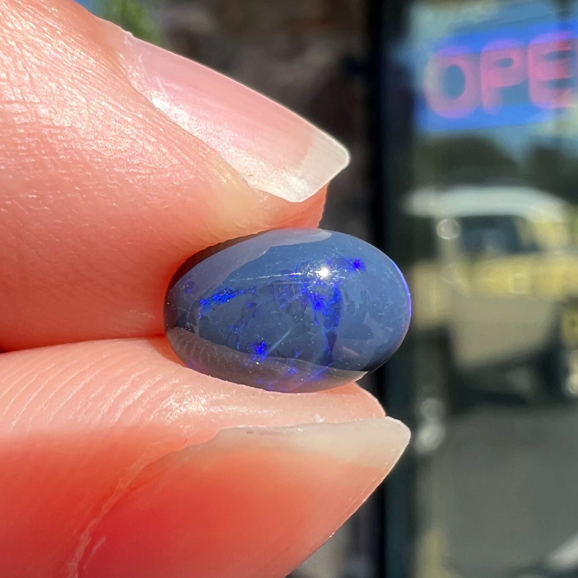 A loose, oval cabochon cut black opal stone from Lightning Ridge, Australia.  The opal has an N2 body tone.