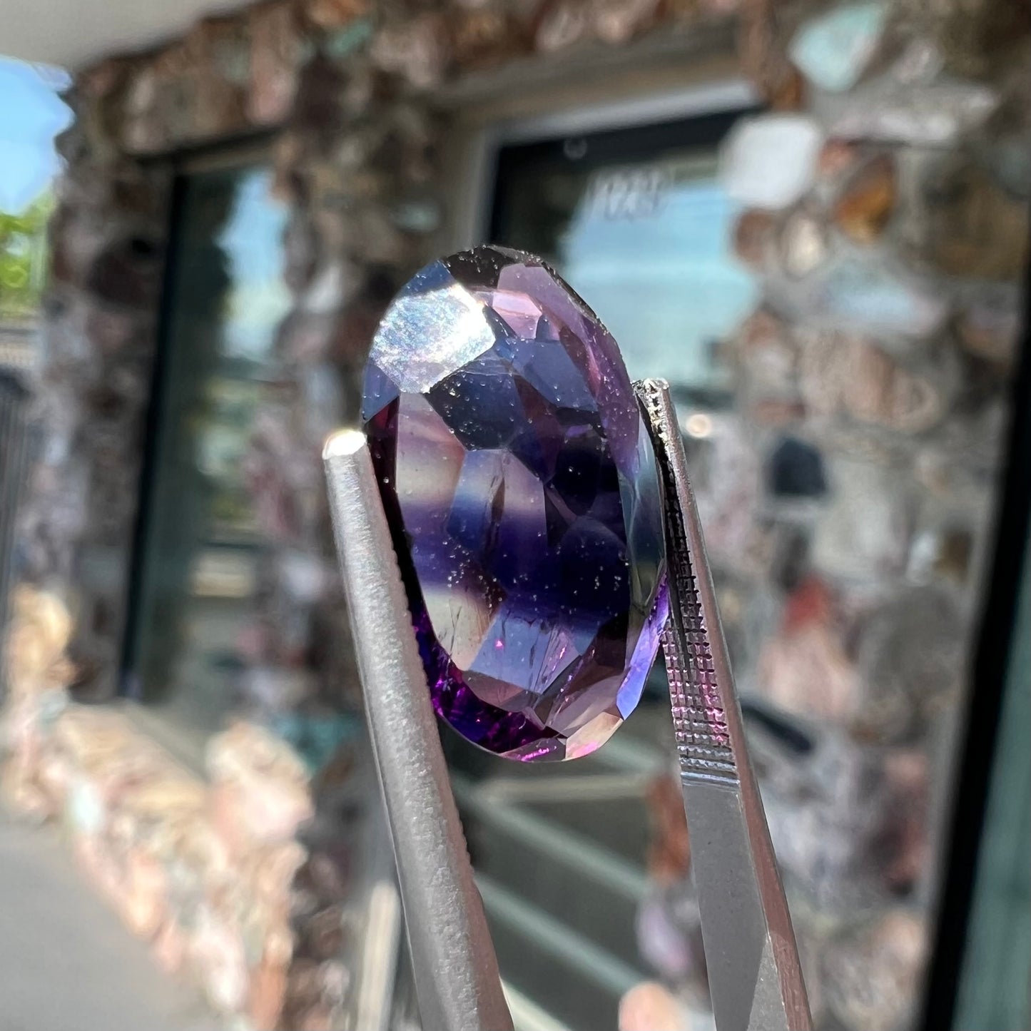 A loose, faceted oval cut Siberian amethyst gemstone.  The stone is purple color with blue and red flashes.