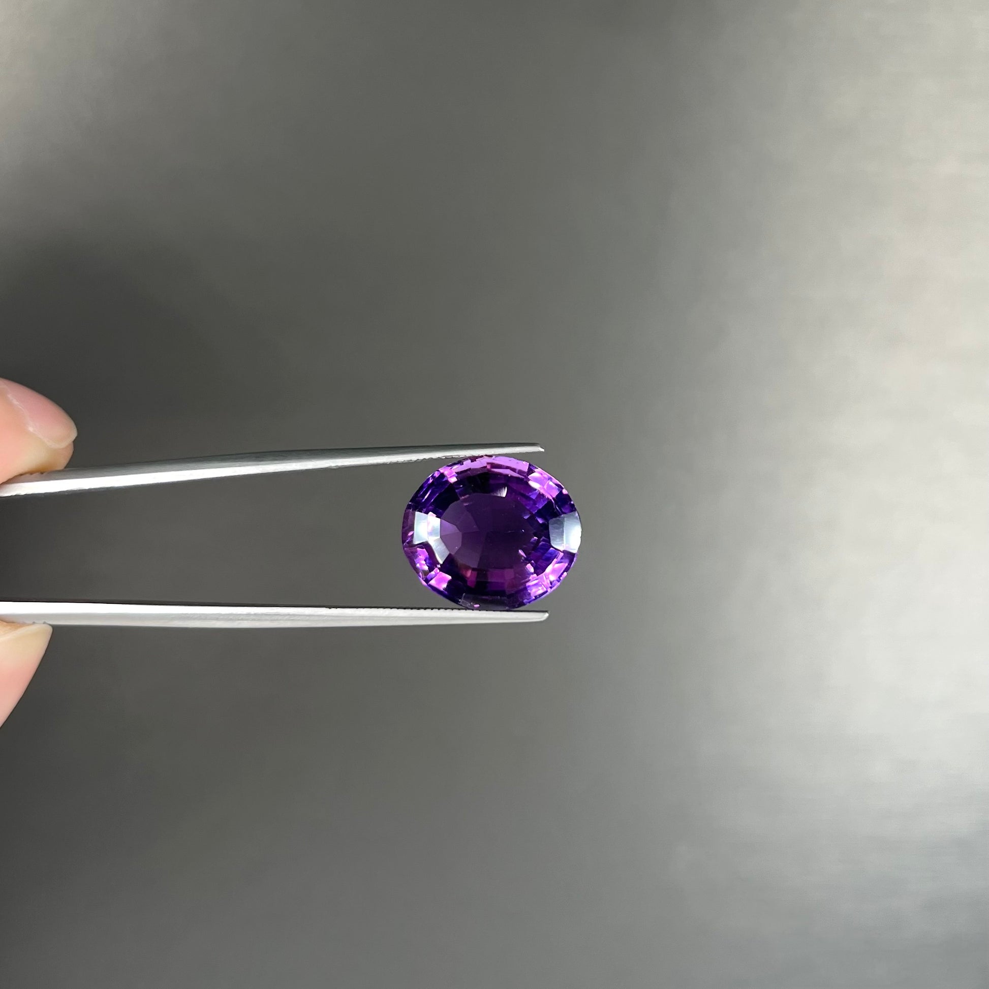 A loose, modified oval cut purple amethyst gemstone.