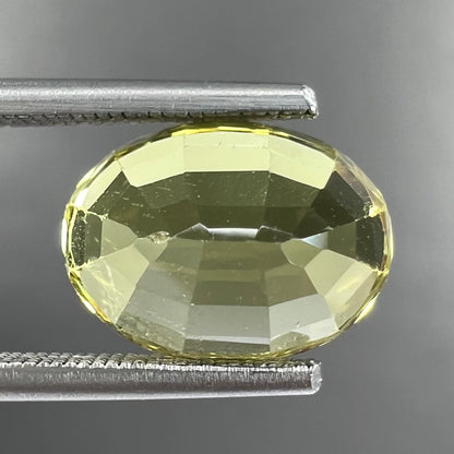 A loose, oval cut greenish yellow chrysoberyl stone.