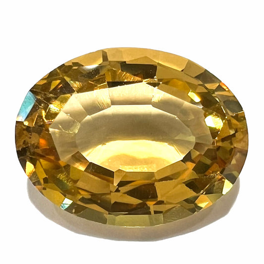 A loose, faceted oval cut golden beryl gemstone.