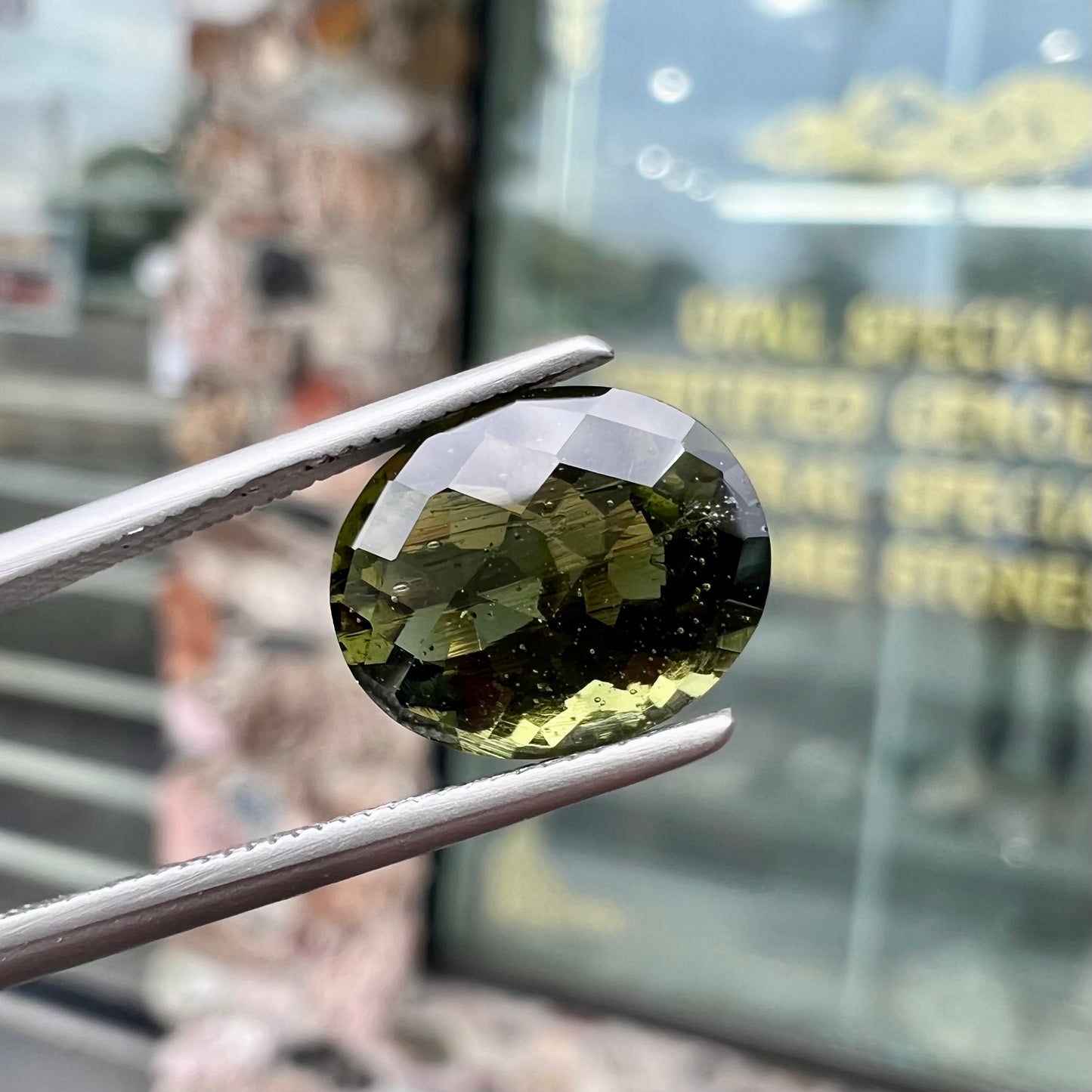 A loose, faceted oval checkerboard moldavite gemstone from the Czech Republic.