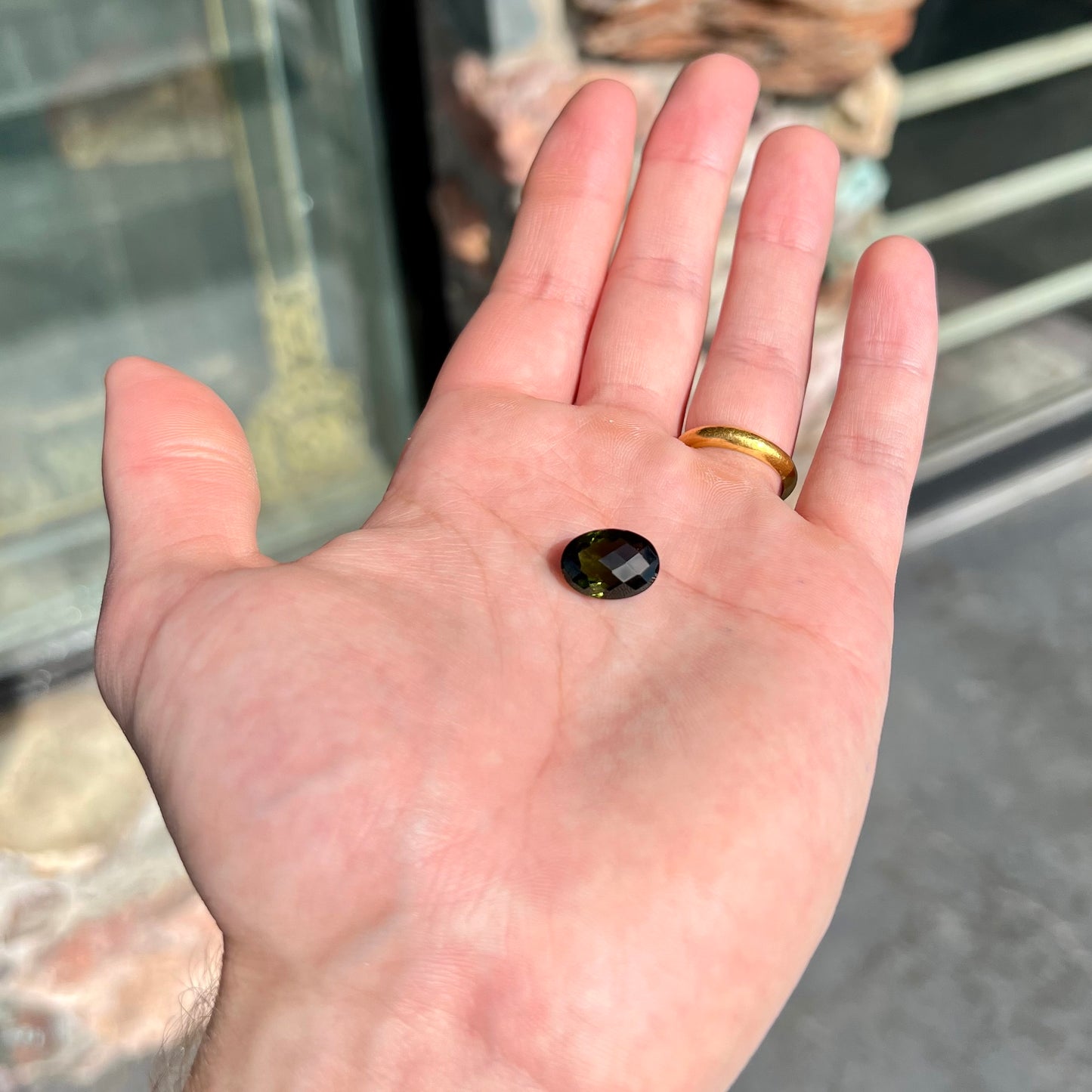 A faceted oval cut natural moldavite gemstone.