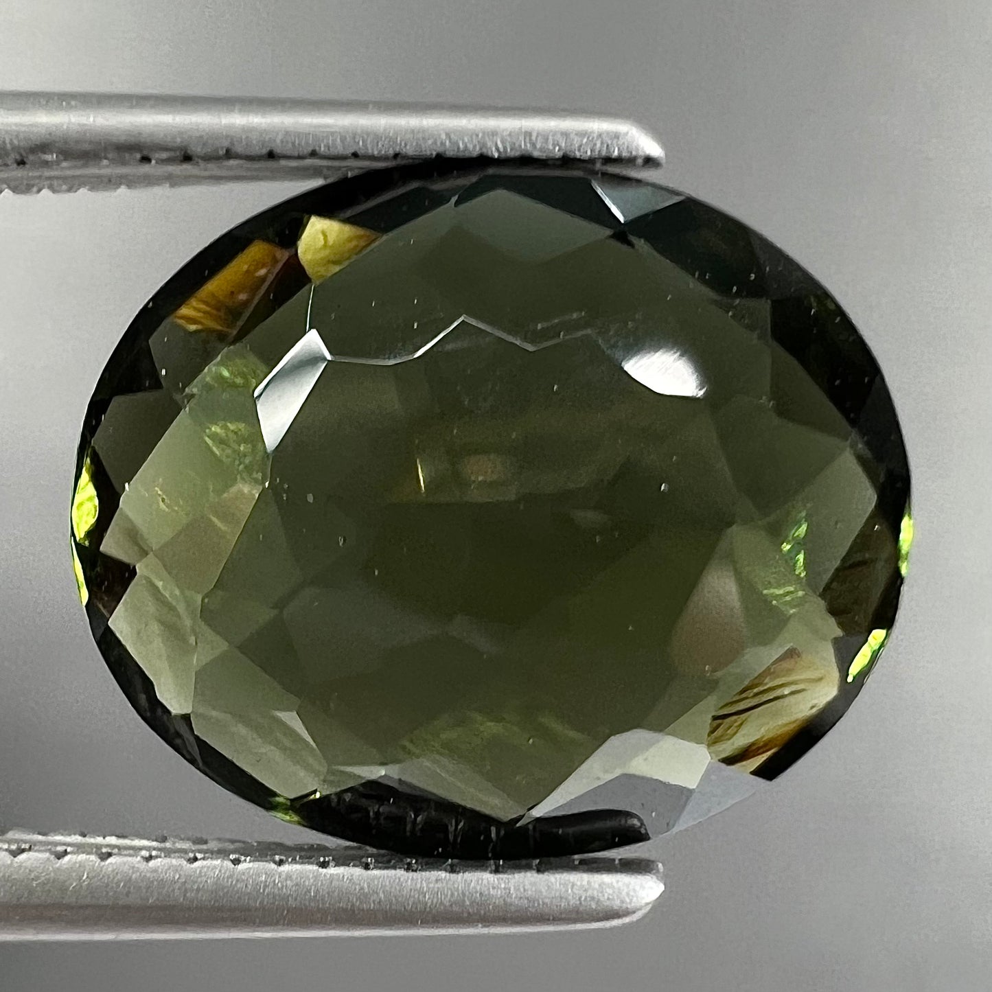 A loose, oval cut natural moldavite gemstone.  The stone weighs 3.85 carats.