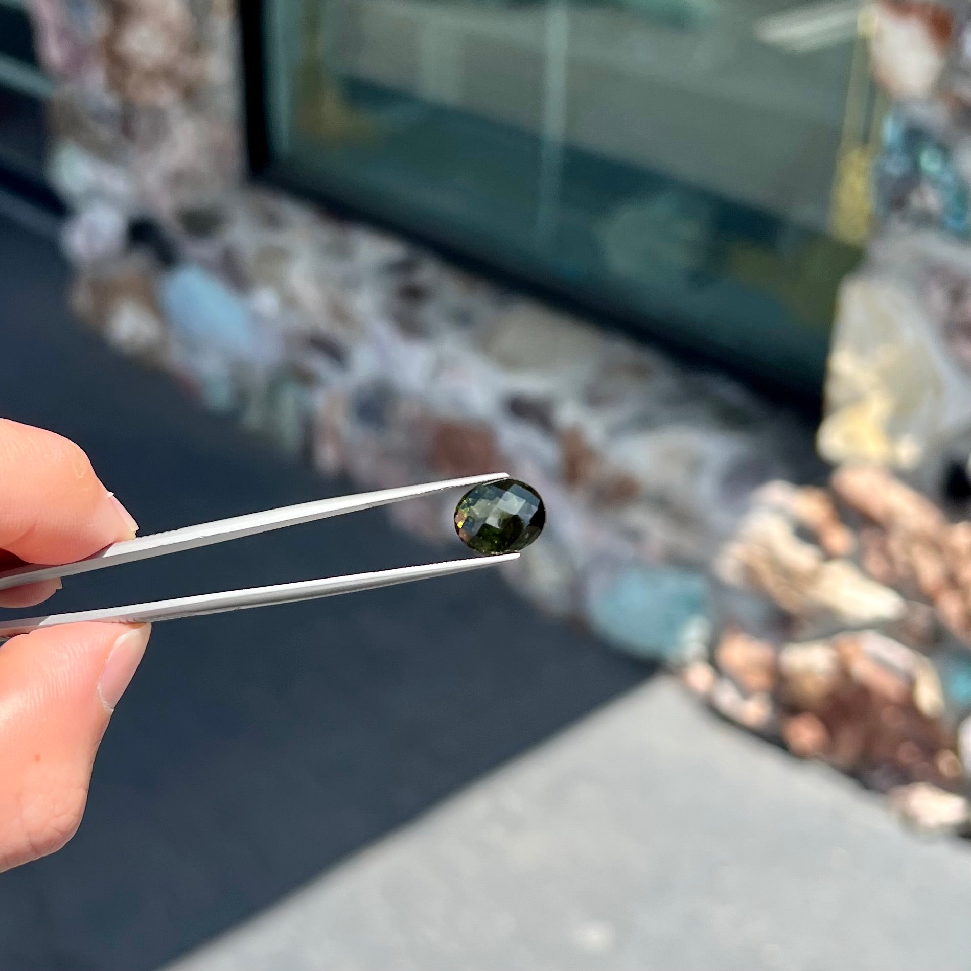A loose, faceted oval cut natural moldavite gemstone.