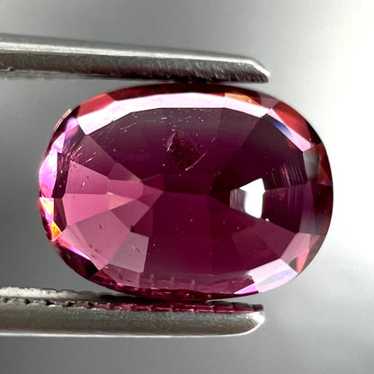 A loose, faceted oval cut purple tourmaline gemstone.  The stone weighs 2.08 carats.