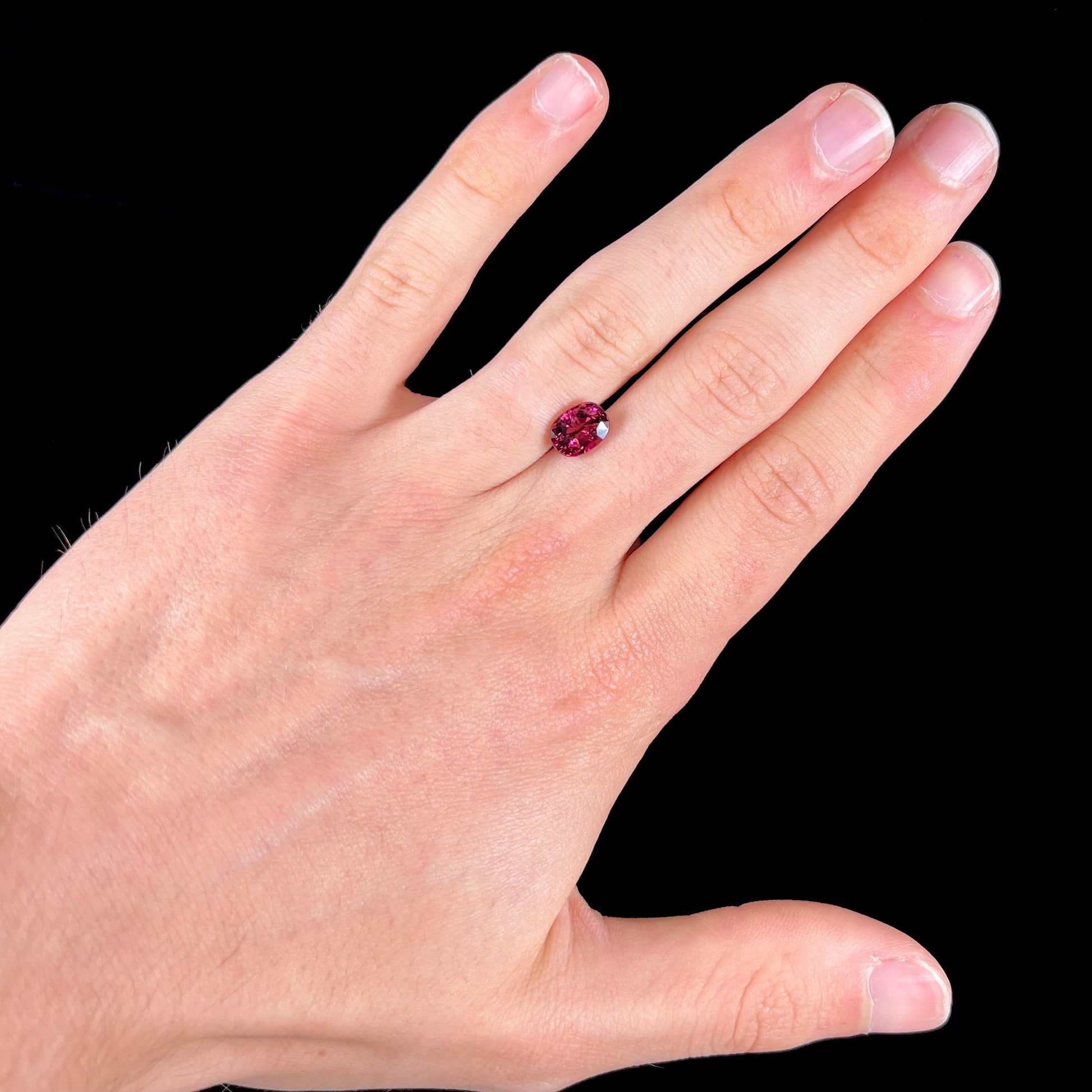 A loose, faceted oval cut purple tourmaline gemstone.  The stone weighs 2.08 carats.