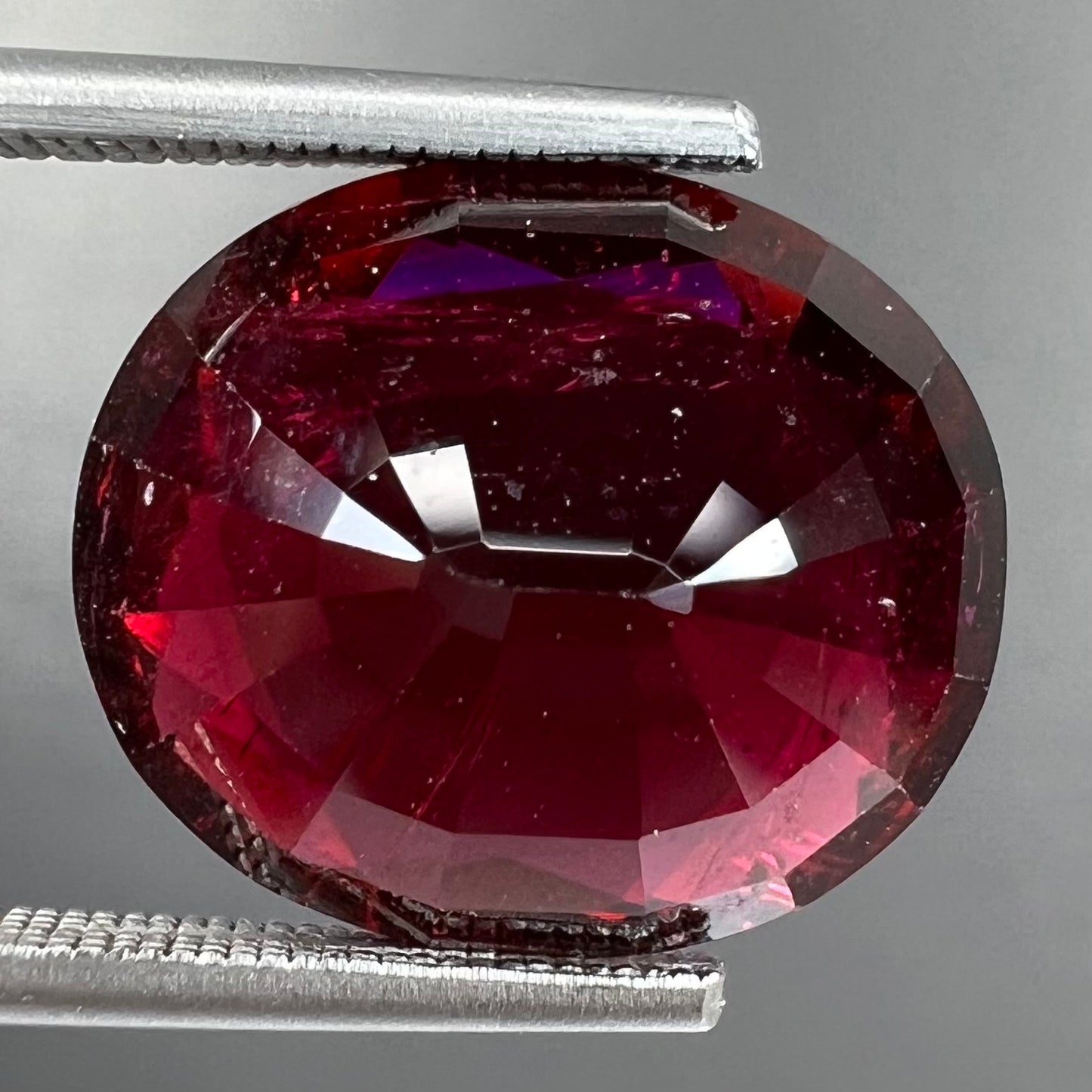 A loose, oval cut purplish red rubellite tourmaline stone.