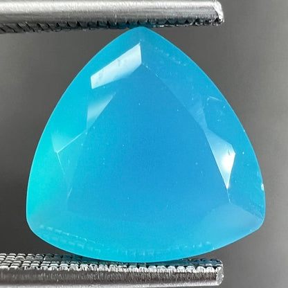 A loose, blue, trillion cut Paraiba chalcedony gemstone.