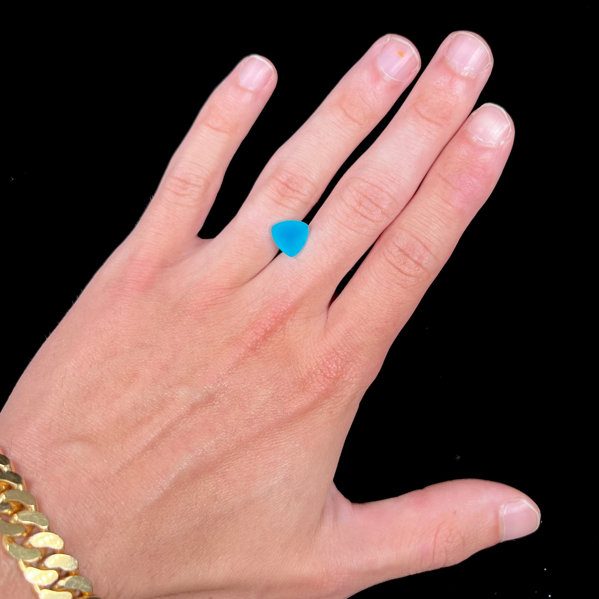 A loose, blue, trillion cut Paraiba chalcedony gemstone.
