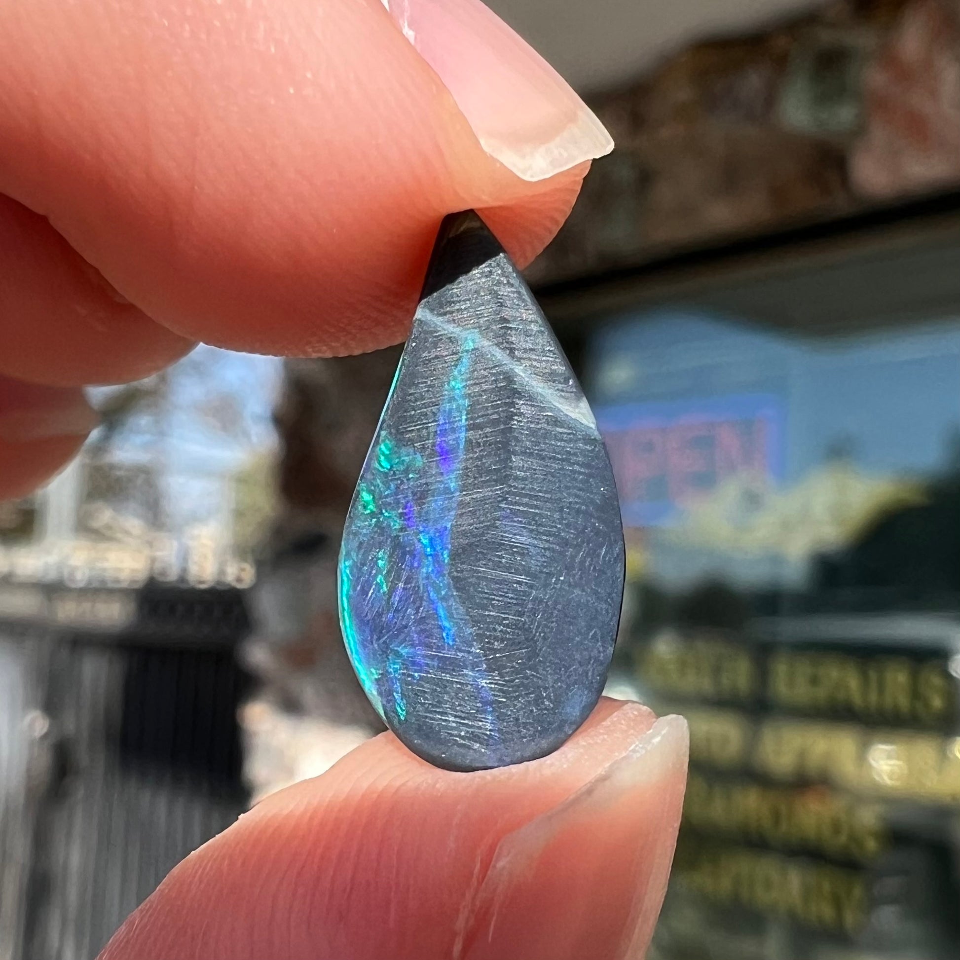 A freeform pear shaped black opal from Lightning Ridge, Australia.