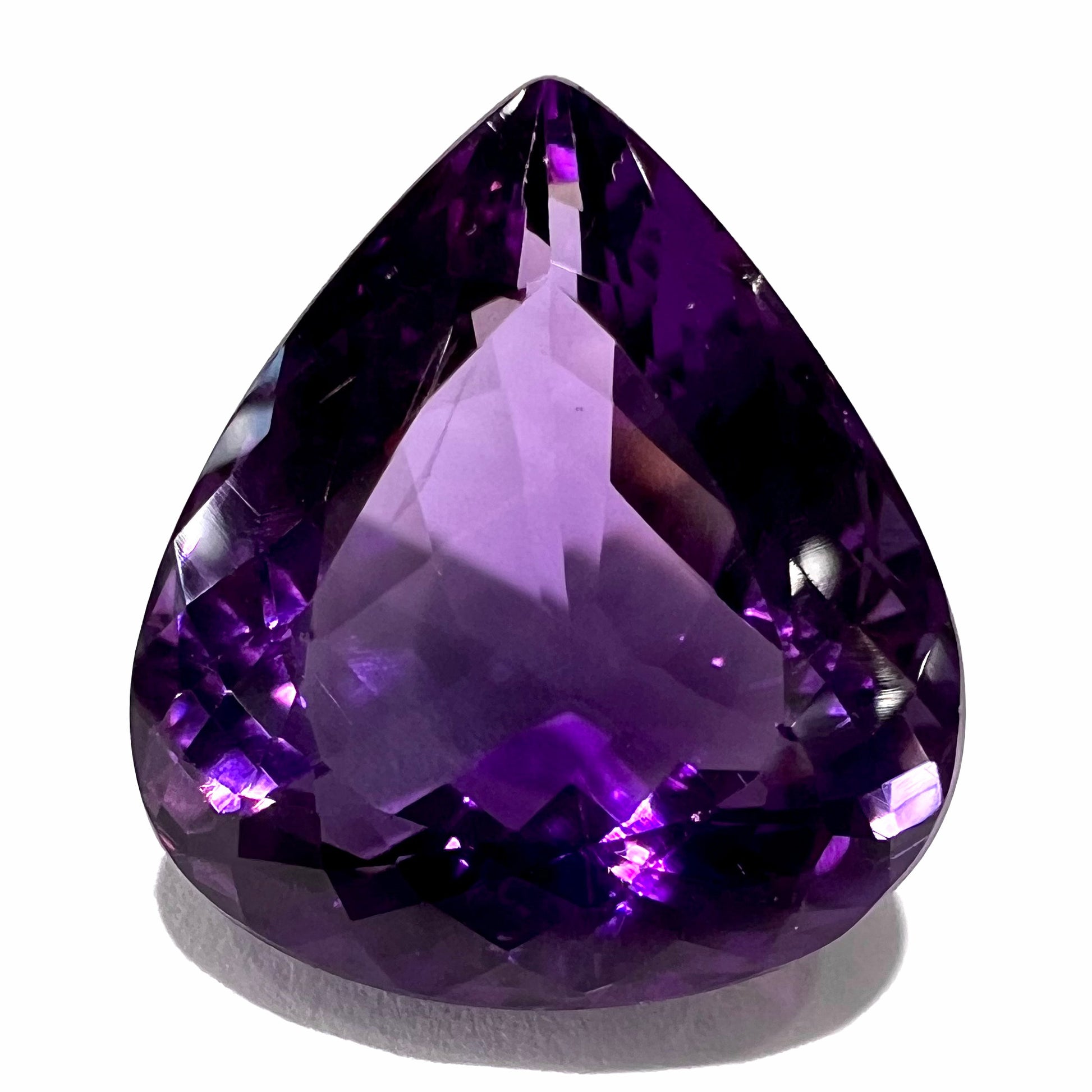 A large, pear shaped amethyst gemstone.  The stone is a dark purple color.