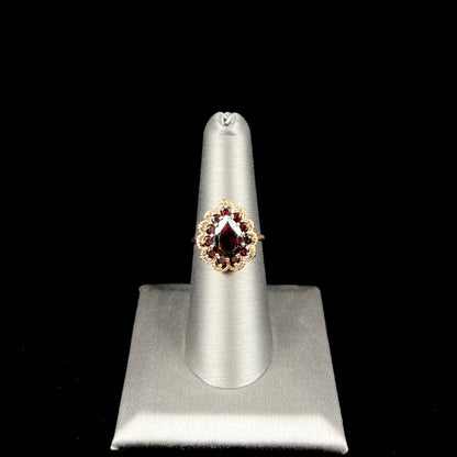 A vintage, 1940's style yellow gold ring set with a pear shaped almandine garnet.  A halo of round garnets surround the center stone.