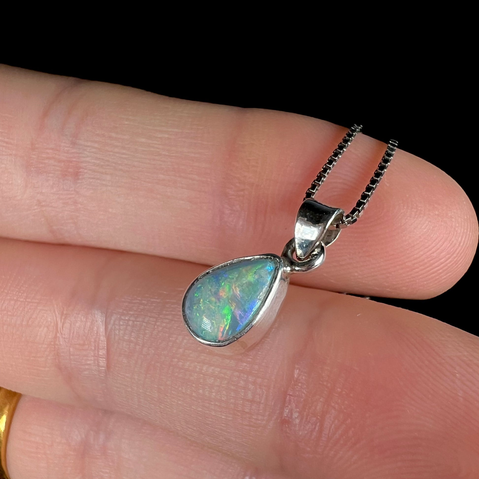 A dainty, sterling silver necklace bezel set with a natural, pear shaped opal stone.