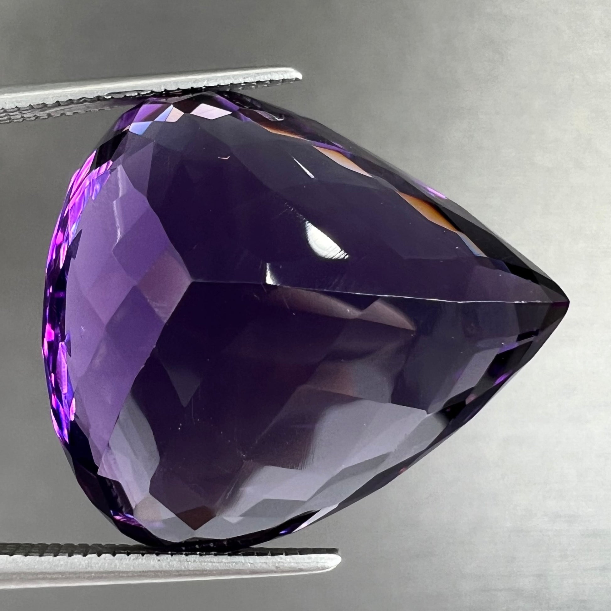 A large, pear shaped amethyst gemstone.  The stone is a dark purple color.