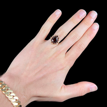 A vintage, 1940's style yellow gold ring set with a pear shaped almandine garnet.  A halo of round garnets surround the center stone.