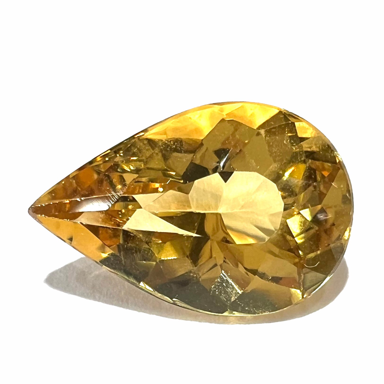A loose, pear shaped golden beryl gemstone.