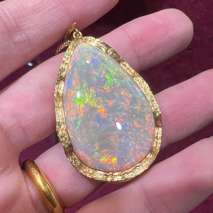 A ladies' natural, pear shaped, gray base Australian opal pendant set in 18 karat yellow gold.
