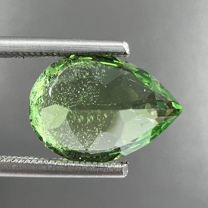 A loose, pear shaped tsavorite garnet gemstone.  The stone is yellowish green.