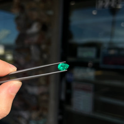 A loose, pear shaped natural emerald gemstone.