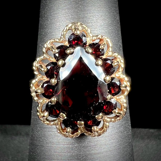 A vintage, 1940's style yellow gold ring set with a pear shaped almandine garnet.  A halo of round garnets surround the center stone.