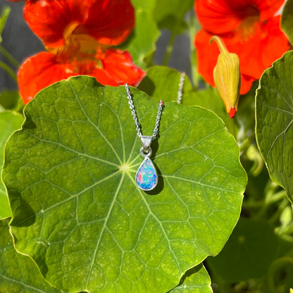 A pear shaped black opal necklace set in sterling silver.  The opal vividly flashes every color of the rainbow.