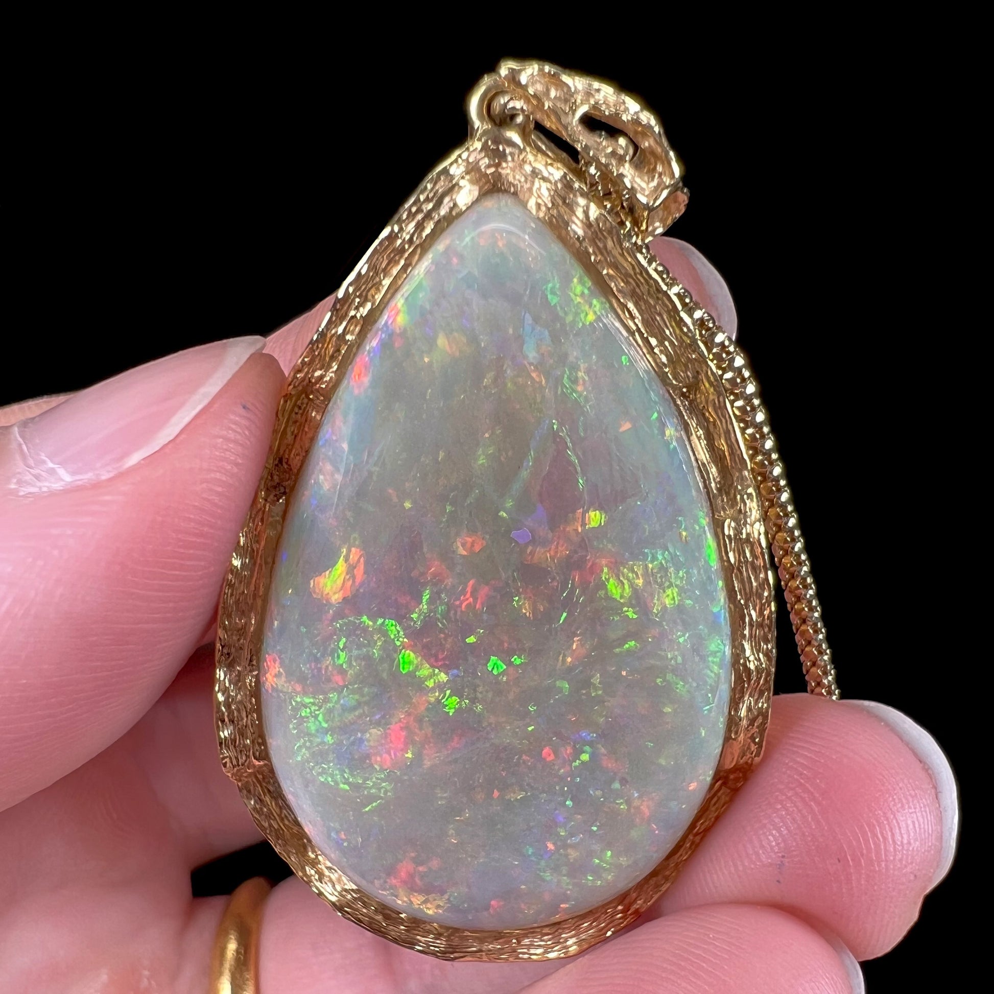 A ladies' natural, pear shaped, gray base Australian opal pendant set in 18 karat yellow gold.