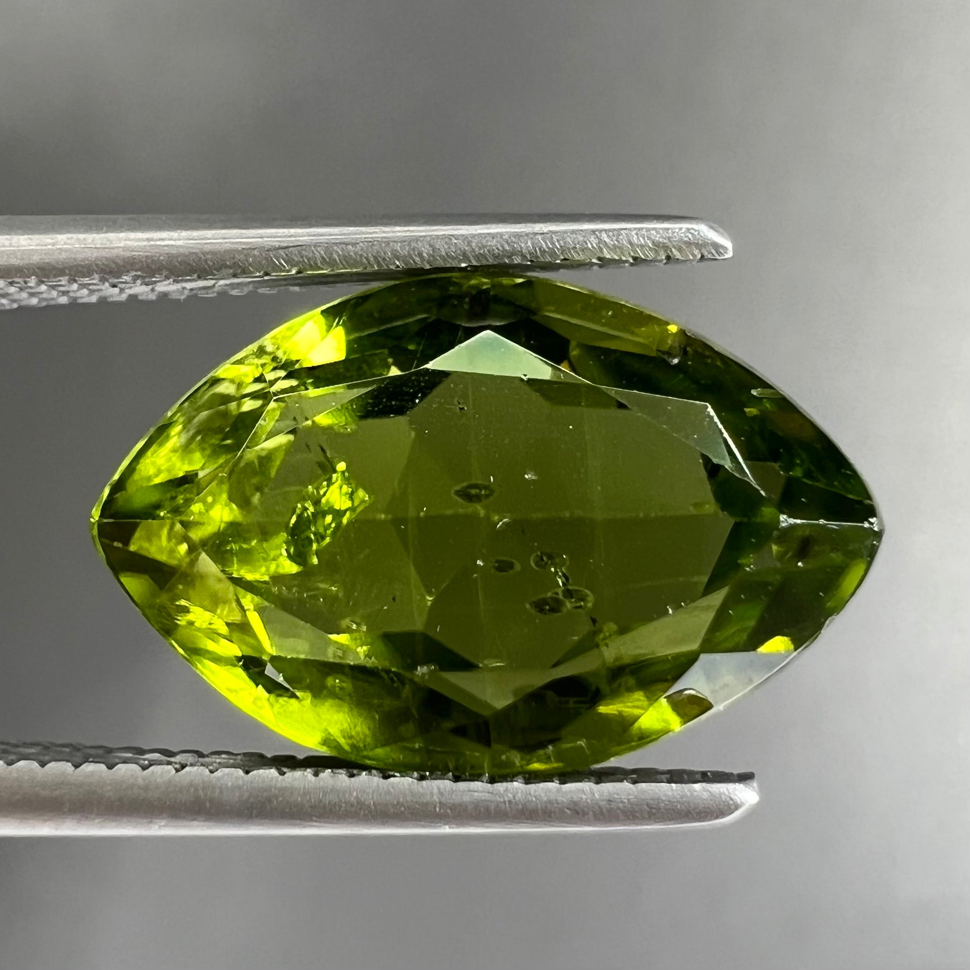 A loose, marquise cut peridot gemstone.  The stone is an olive green color.
