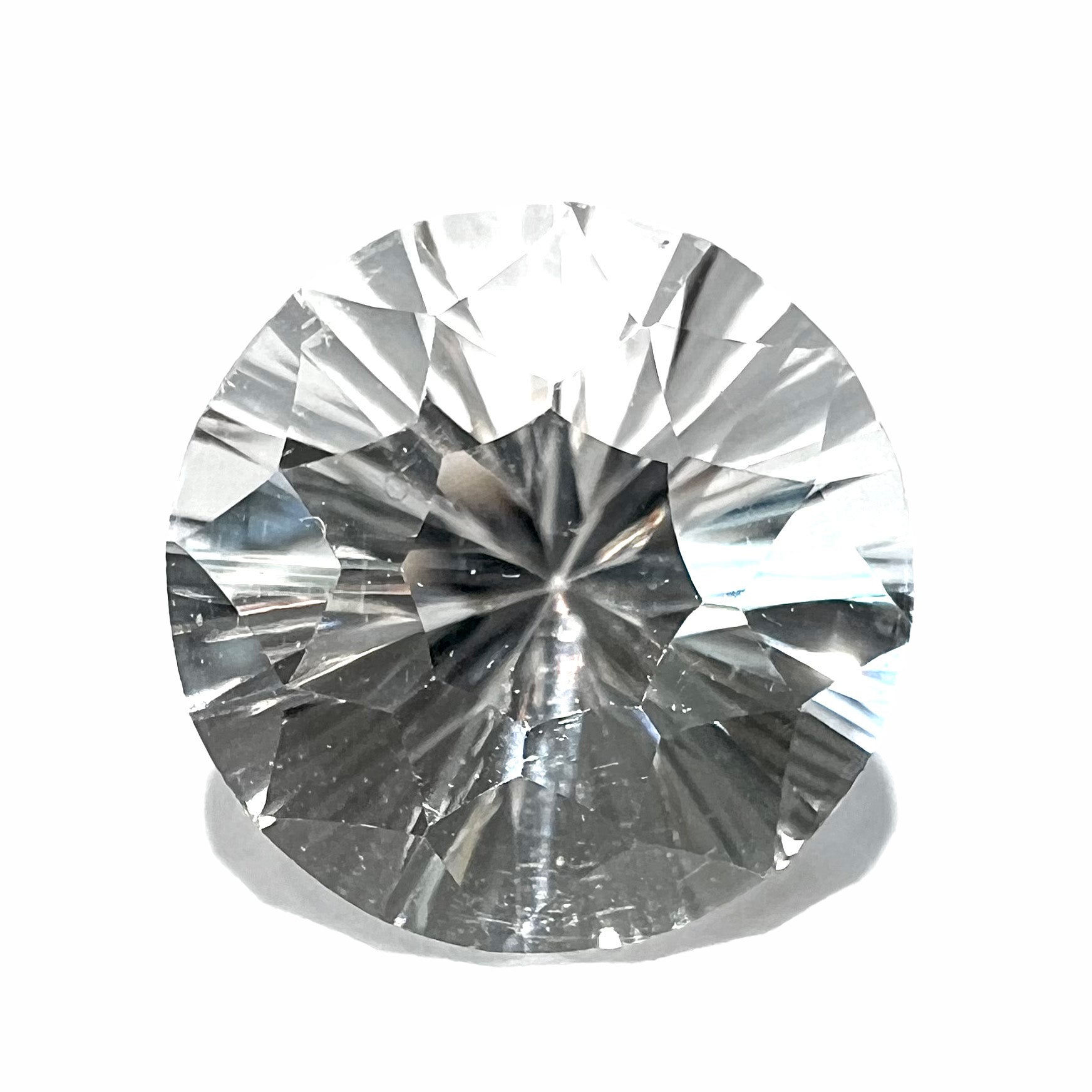 A round brilliant cut petalite gemstone.  The stone is colorless.