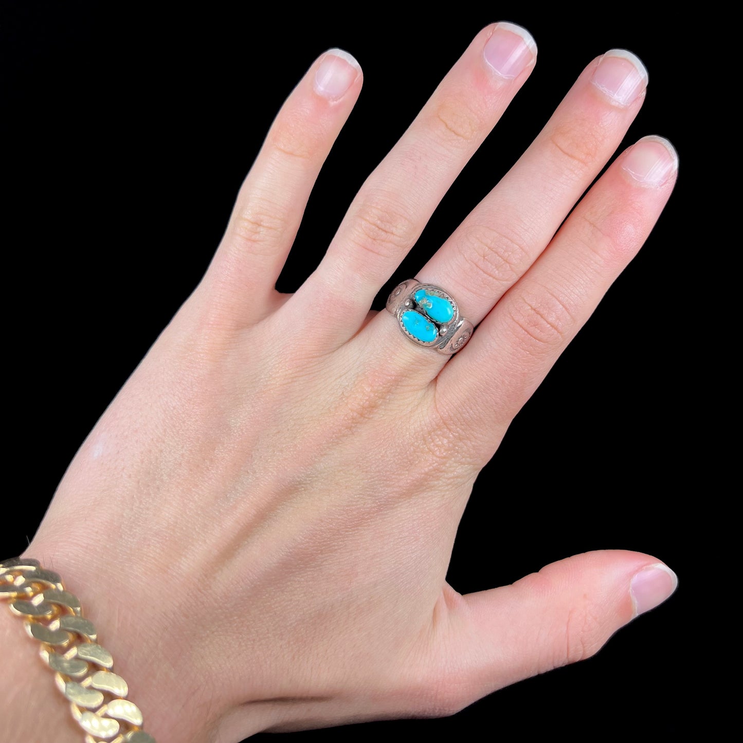 A unisex sterling silver ring bezel set with two Pilot Mountain turquoise stones.  The ring is stamped with sun patterns.