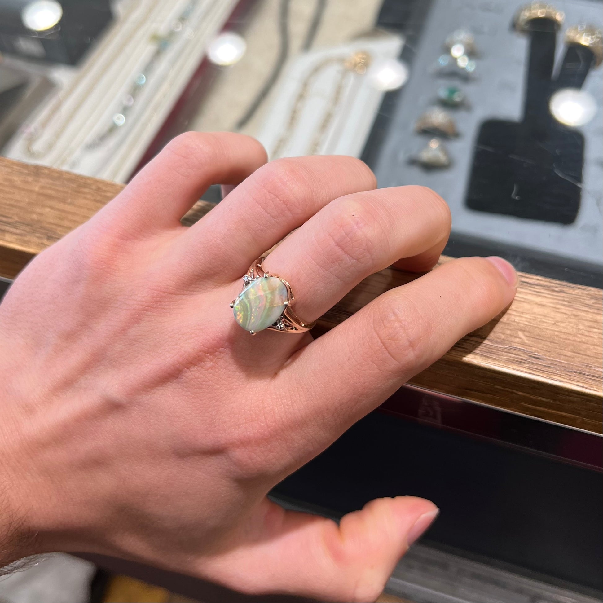 A ladies' Australian boulder opal ring set in yellow gold with diamond accents.  The opal shimmers green and pink and has fissure inclusions.