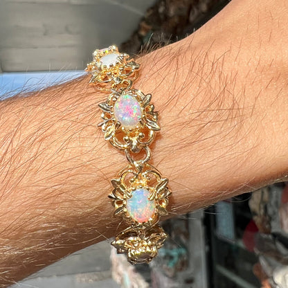 A ladies' yellow gold bracelet set with natural, oval cabochon cut white crystal opals.