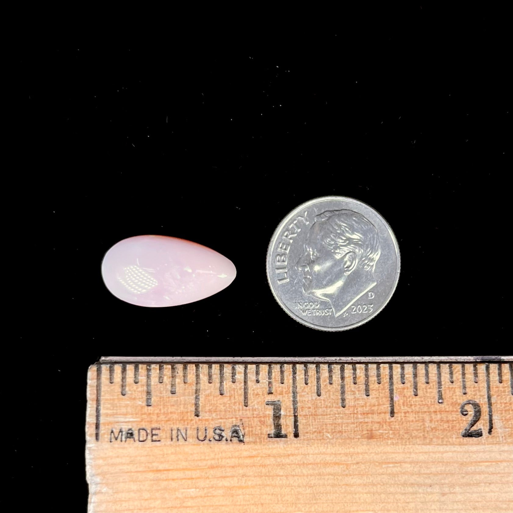 A loose, pear shaped pink Peruvian opal cabochon.  The opal has green play of color.