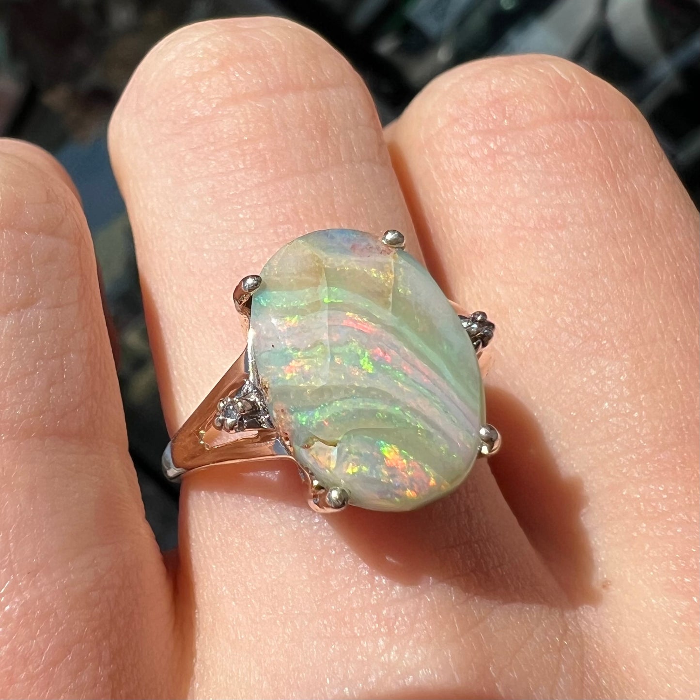 A ladies' Australian boulder opal ring set in yellow gold with diamond accents.  The opal shimmers green and pink and has fissure inclusions.